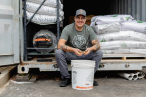 Tony P, Production Manager at Bent Water Brewing sits in front of bags of malt outside the brewery